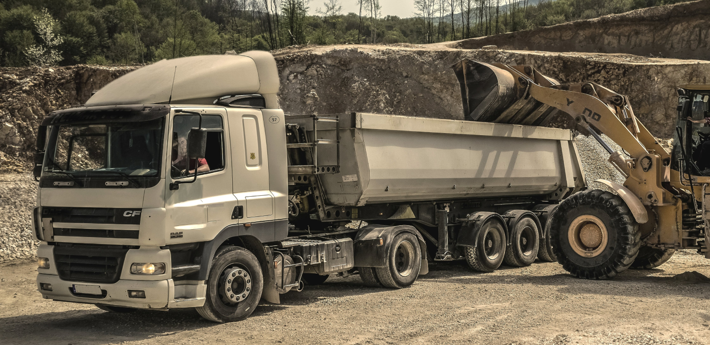 koparka wsypujaca ziemię do przyczepy samochodu ciężarowego